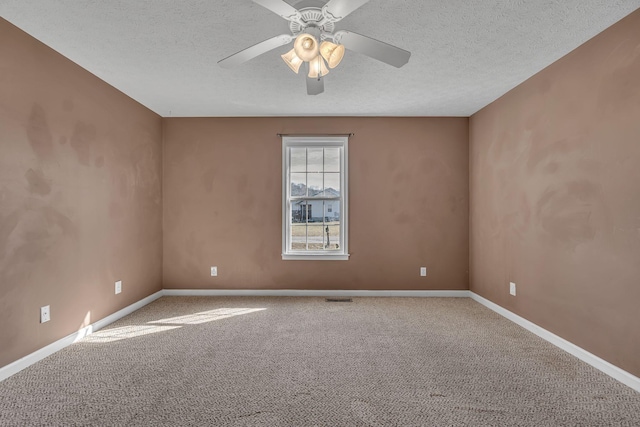 carpeted spare room featuring visible vents, a textured ceiling, baseboards, and a ceiling fan