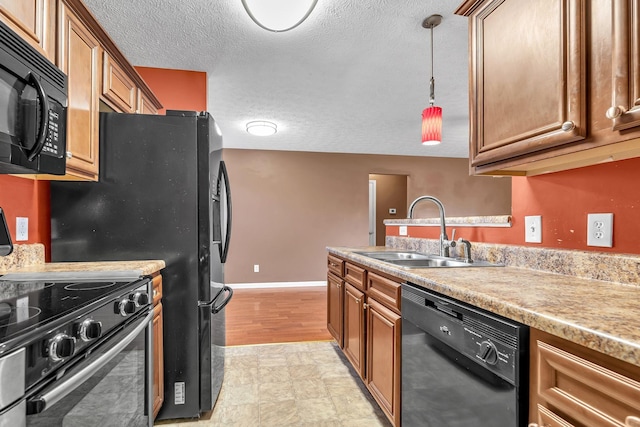 kitchen featuring brown cabinetry, a sink, black appliances, light countertops, and a textured ceiling