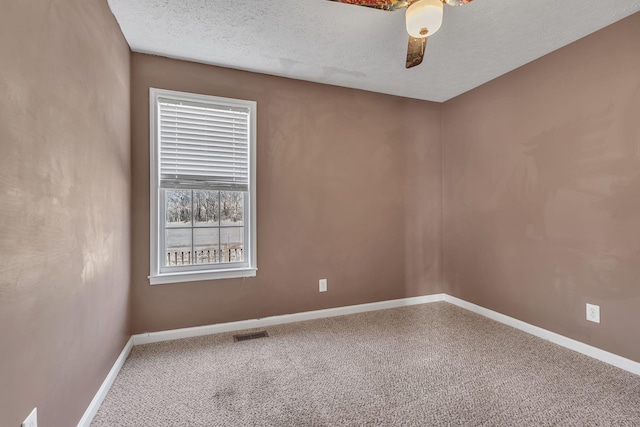 unfurnished room with visible vents, baseboards, carpet floors, and a textured ceiling