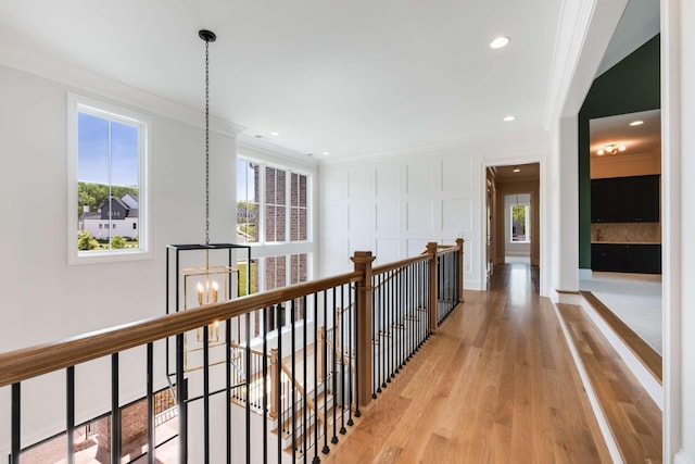 hall featuring light hardwood / wood-style floors, ornamental molding, and an inviting chandelier