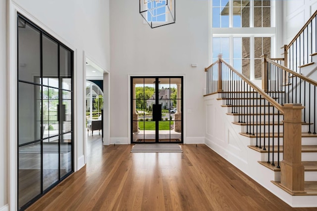 entryway with hardwood / wood-style floors, a towering ceiling, and french doors