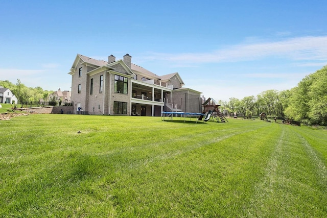 back of house with a trampoline, a playground, a balcony, and a lawn