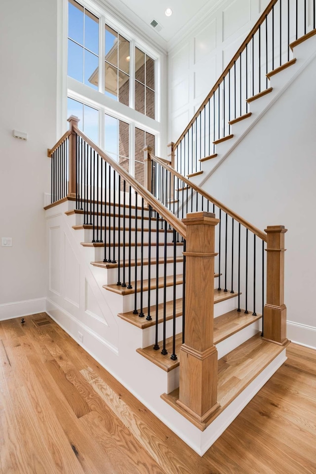 stairs featuring wood-type flooring and ornamental molding