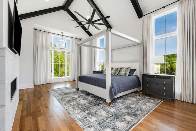 bedroom featuring multiple windows, hardwood / wood-style floors, and beamed ceiling