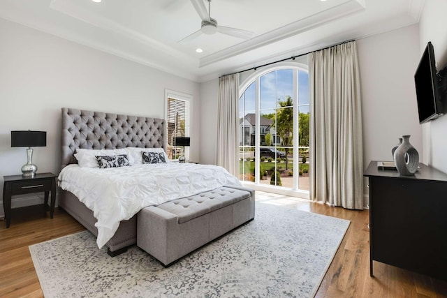 bedroom featuring light hardwood / wood-style floors, a raised ceiling, and ceiling fan