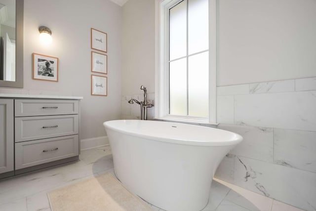 bathroom with vanity, a tub to relax in, and tile walls