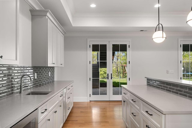 kitchen with sink, french doors, pendant lighting, light hardwood / wood-style floors, and white cabinets