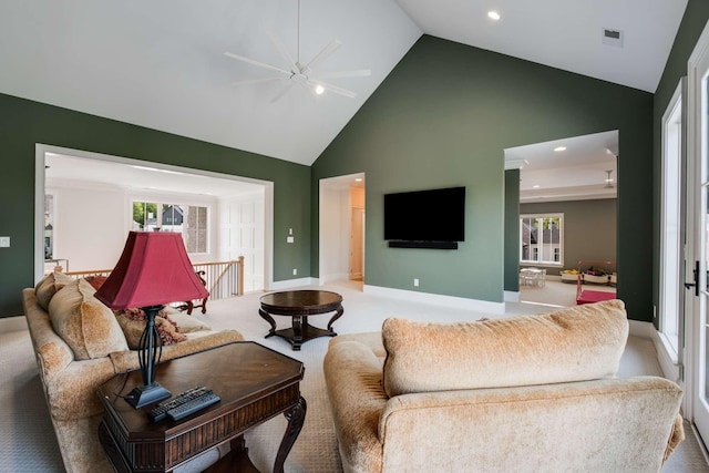 carpeted living room with ceiling fan and high vaulted ceiling