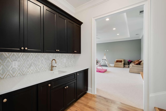 bar featuring light carpet, decorative backsplash, ornamental molding, and sink