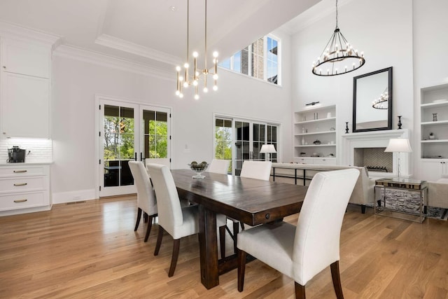 dining room featuring a notable chandelier, light hardwood / wood-style floors, crown molding, and french doors