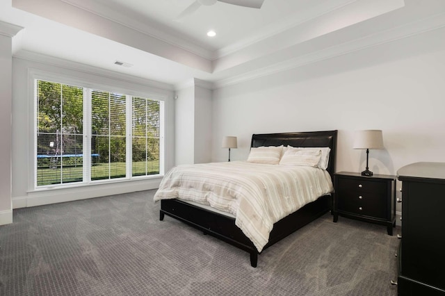 bedroom featuring a tray ceiling, ceiling fan, ornamental molding, and dark colored carpet