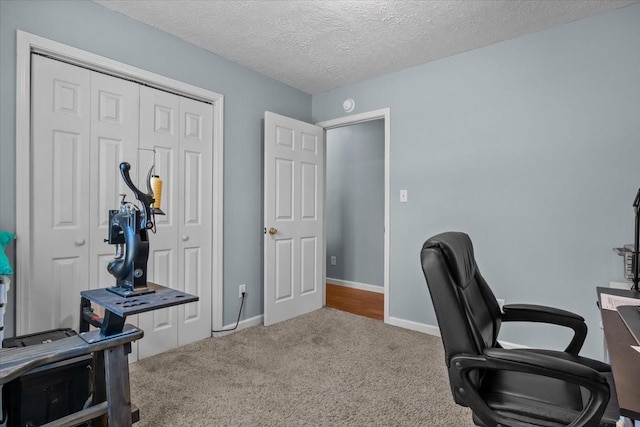 carpeted home office featuring a textured ceiling