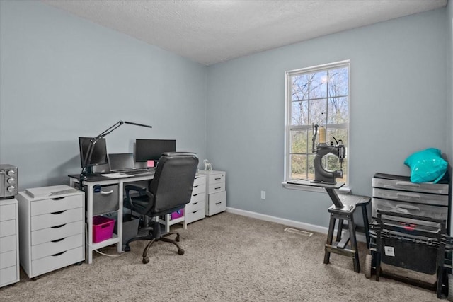 carpeted home office featuring a textured ceiling