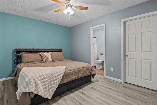 bedroom with ceiling fan, light hardwood / wood-style floors, a textured ceiling, and ensuite bath