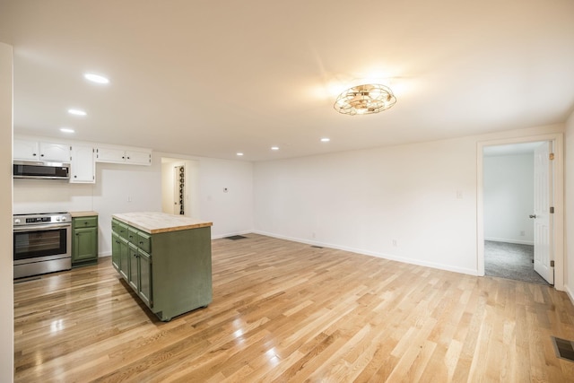 kitchen with white cabinets, green cabinets, appliances with stainless steel finishes, and light hardwood / wood-style flooring