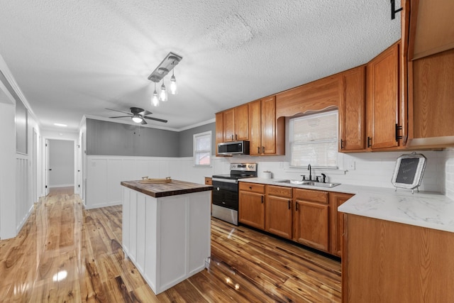 kitchen with stainless steel appliances, light hardwood / wood-style flooring, ceiling fan, and sink