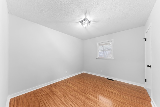 empty room featuring a textured ceiling and hardwood / wood-style flooring