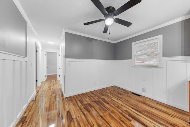 empty room with light wood-type flooring, ceiling fan, and crown molding