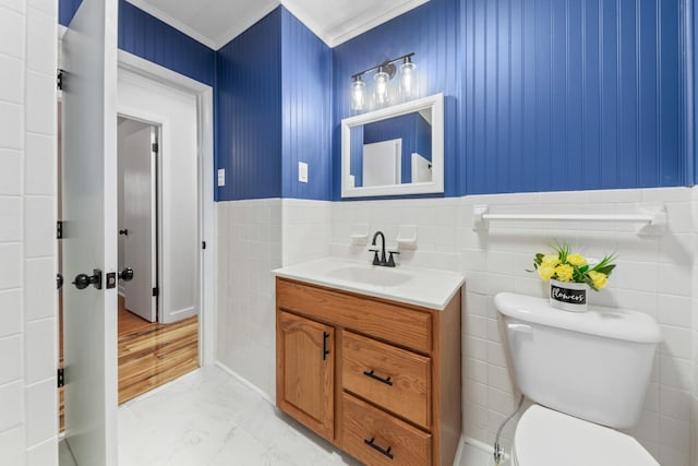 bathroom featuring vanity, toilet, tile walls, and ornamental molding