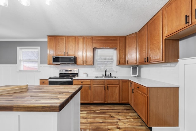 kitchen with sink, stainless steel appliances, dark hardwood / wood-style flooring, wooden counters, and ornamental molding