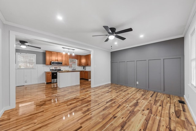 unfurnished living room with a wealth of natural light, crown molding, and light wood-type flooring