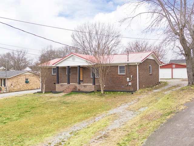 view of front of house with an outbuilding, covered porch, a front yard, and a garage