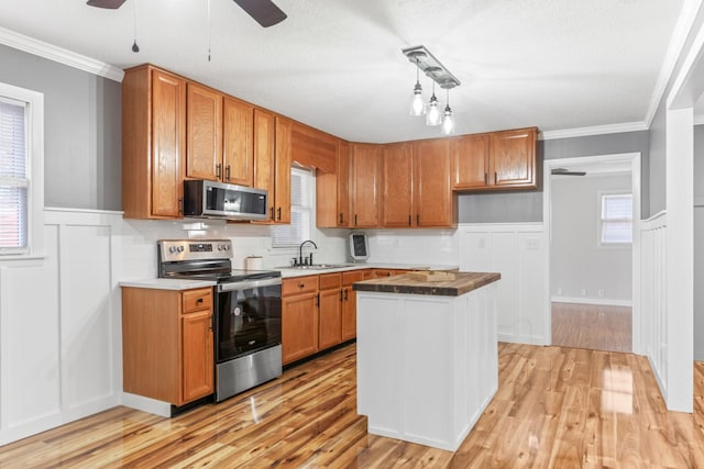 kitchen with sink, light hardwood / wood-style flooring, stainless steel appliances, and ornamental molding