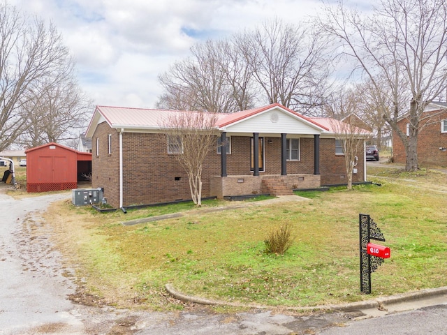 view of front of home with a front lawn, covered porch, and a storage shed