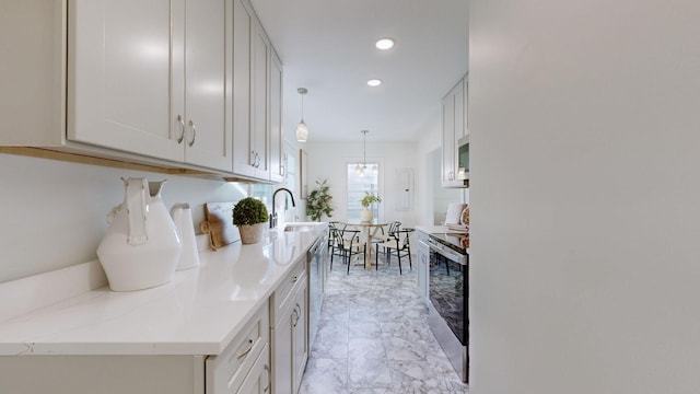 kitchen with pendant lighting, white cabinets, sink, light stone countertops, and stainless steel appliances