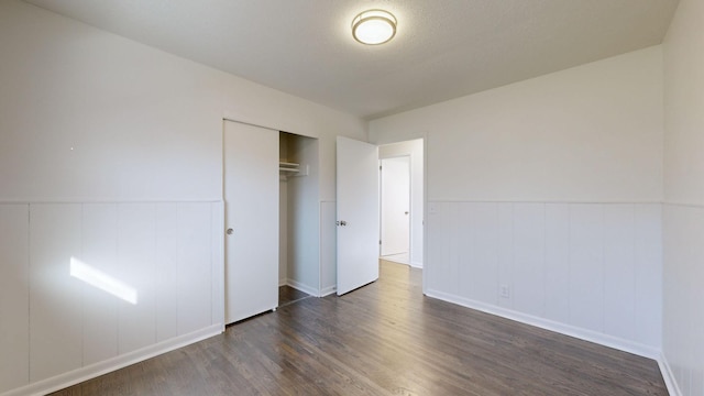 unfurnished bedroom featuring dark hardwood / wood-style floors, a textured ceiling, and a closet