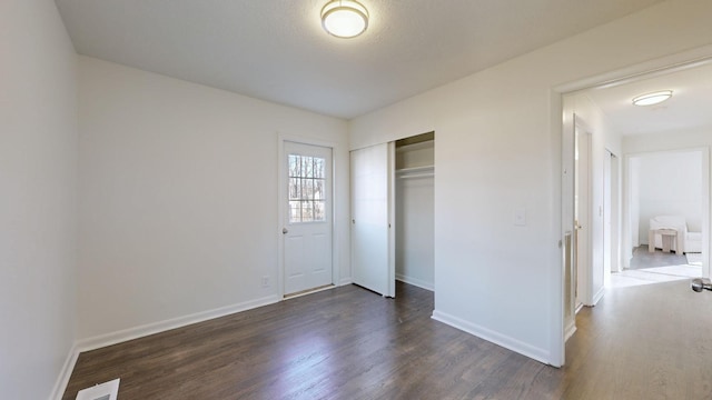 unfurnished bedroom featuring dark hardwood / wood-style flooring and a closet