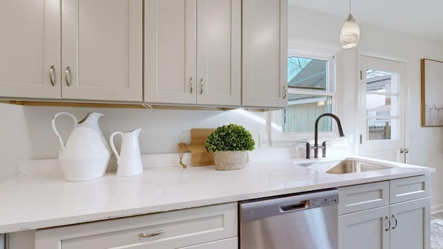 kitchen with light stone countertops, dishwasher, pendant lighting, and sink