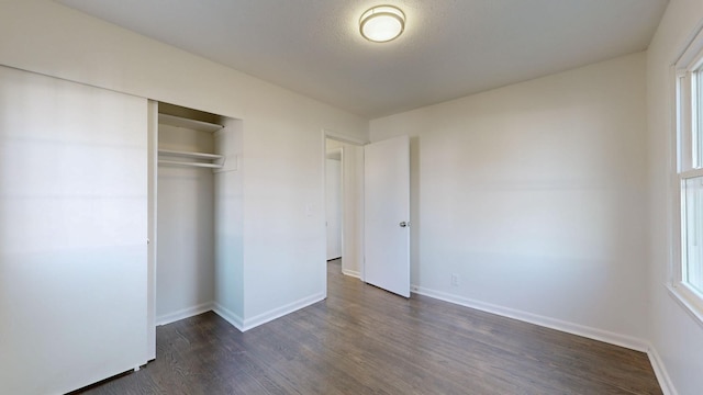 unfurnished bedroom with dark hardwood / wood-style floors, a textured ceiling, and a closet