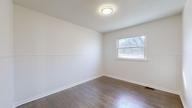 empty room with dark hardwood / wood-style flooring and a textured ceiling