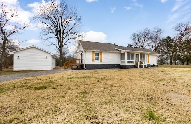 view of front of house featuring a sunroom, an outbuilding, and a front yard