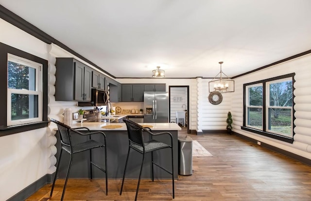 kitchen featuring kitchen peninsula, appliances with stainless steel finishes, a breakfast bar, crown molding, and hanging light fixtures