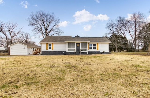 single story home featuring a sunroom, an outbuilding, a front lawn, and a garage