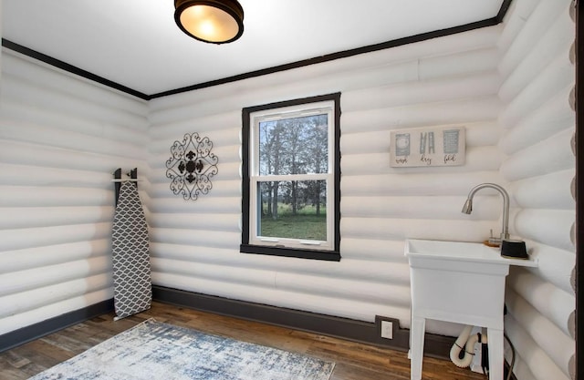 bathroom with log walls and wood-type flooring