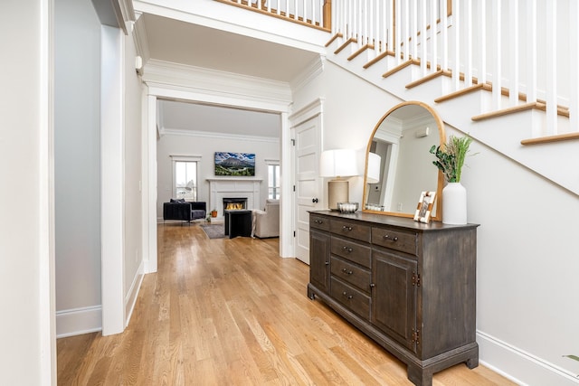 corridor with light hardwood / wood-style floors and crown molding