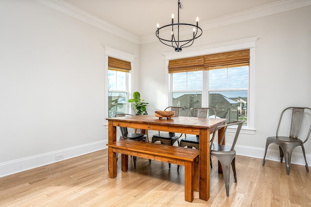 dining area with crown molding, plenty of natural light, light wood-type flooring, and a notable chandelier