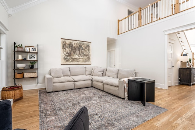 living room with a towering ceiling, hardwood / wood-style flooring, and ornamental molding