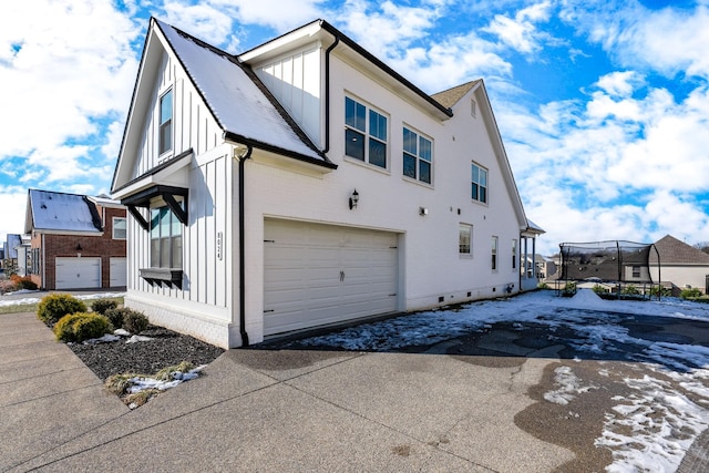 view of side of home featuring a garage and a trampoline