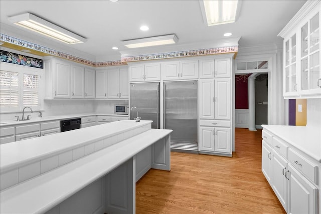 kitchen with sink, white cabinetry, crown molding, built in appliances, and light wood-type flooring