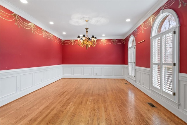 spare room featuring a chandelier and light hardwood / wood-style floors