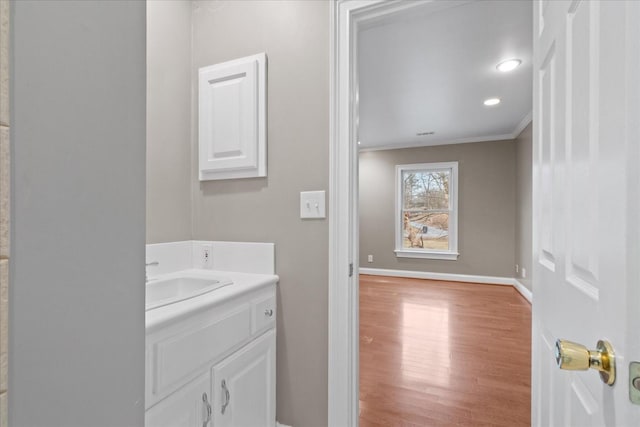 bathroom with vanity, wood-type flooring, and ornamental molding