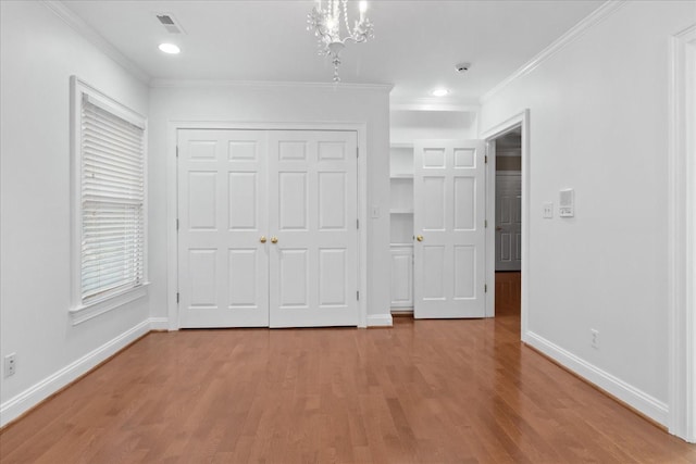 unfurnished bedroom featuring hardwood / wood-style flooring, ornamental molding, and a closet