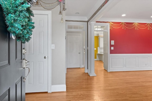 foyer entrance featuring ornamental molding, light hardwood / wood-style floors, and ornate columns