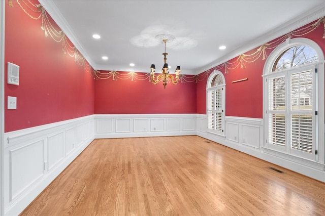 unfurnished dining area with an inviting chandelier, hardwood / wood-style flooring, and crown molding