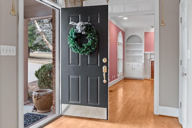 foyer entrance with ornamental molding and light hardwood / wood-style flooring