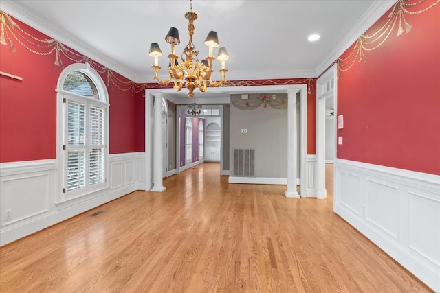 unfurnished dining area with a chandelier, decorative columns, and light hardwood / wood-style flooring